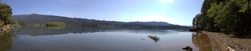 Wide view of Lake Pillsbury, calm water ringed by forested hills and distant peaks.